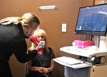 A staff member using the Eccovision Rhinopharyngometry on a female patient during an appointment