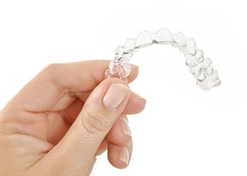 Hand holding a clear aligner