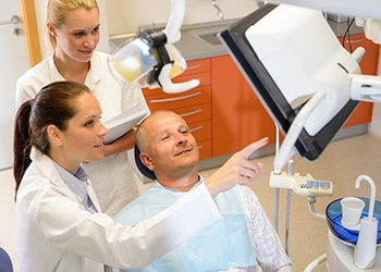 A dentist and dental assistant going over the treatment plan with a male patient