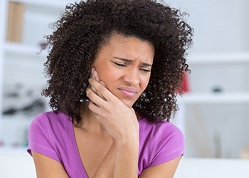 Woman holding cheek in pain