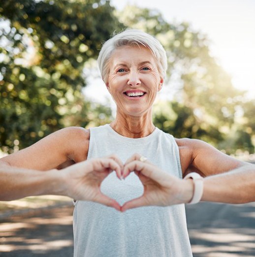 Smiling lady makes shape of heart with her hands
