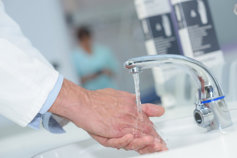 a dental staff member washing their hands prior to seeing a patient