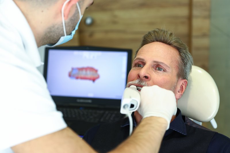 a dentist using a digital impression system on a male patient