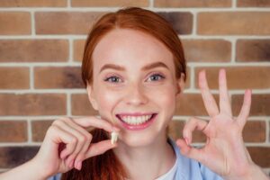 Woman smiling and holding a tooth model