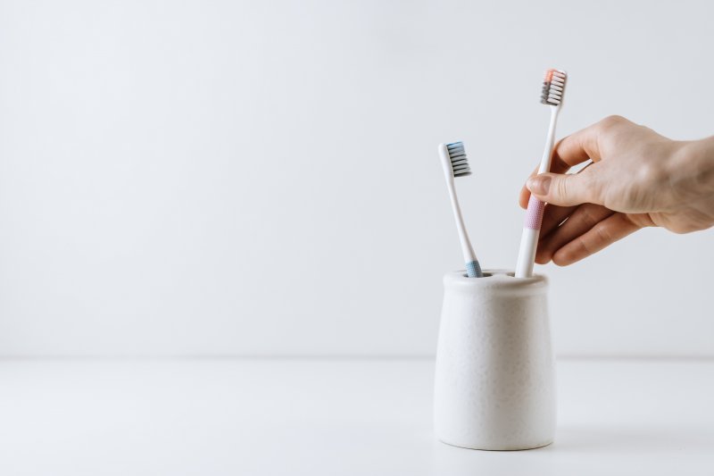 A hand placing a toothbrush in a storage container